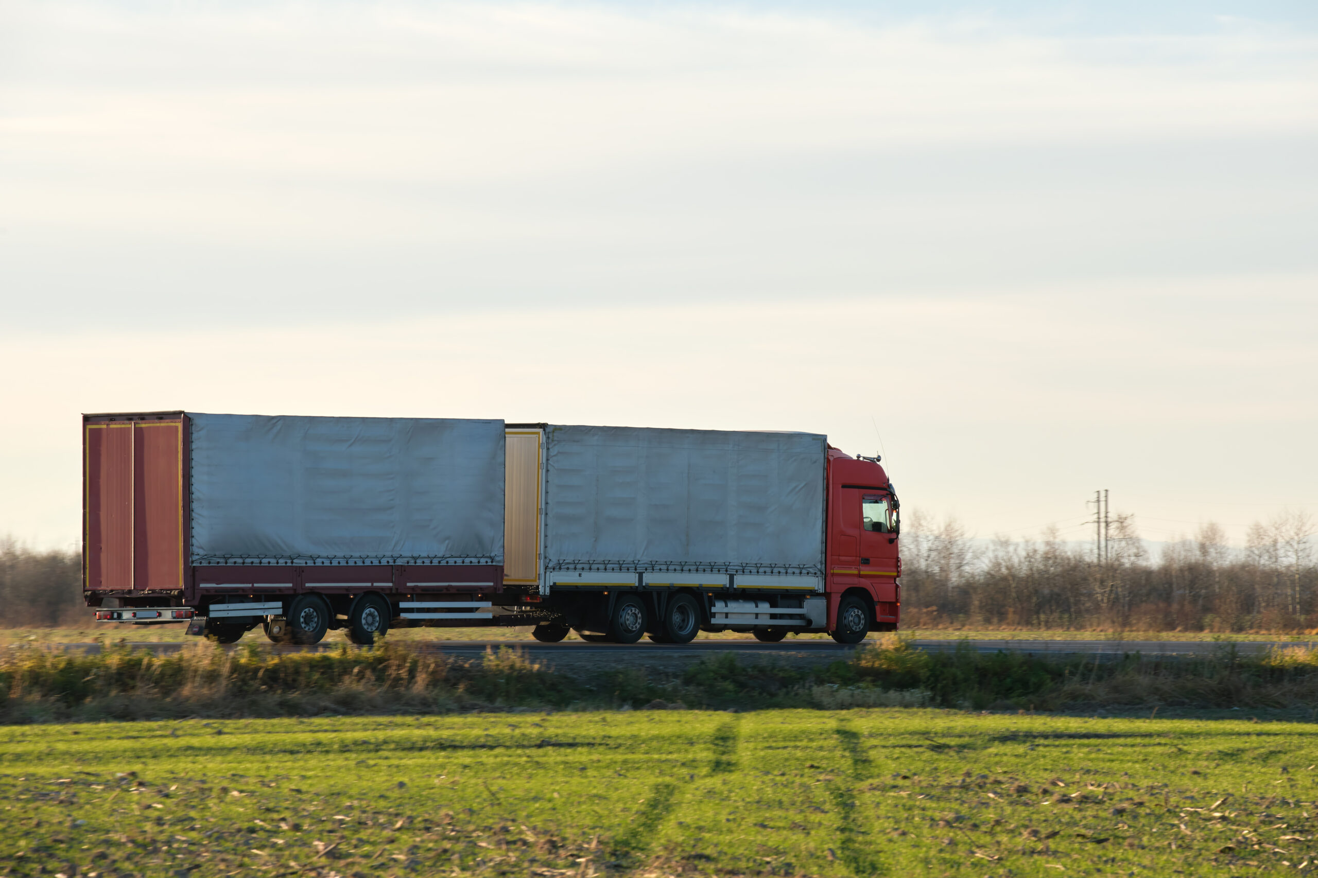 Semi-truck with cargo trailer driving on highway hauling goods in evening. Delivery transportation and logistics concept.